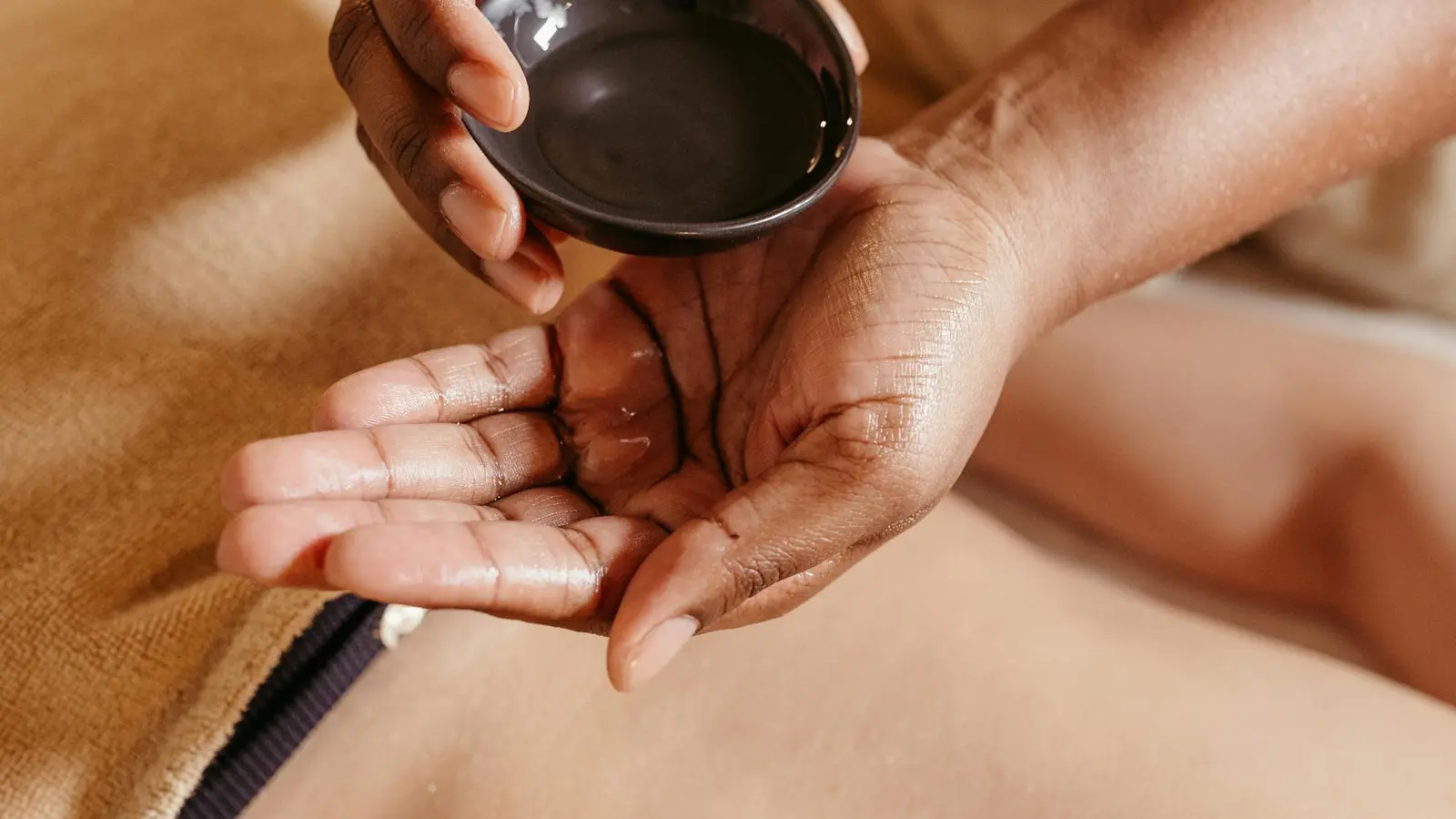 Massage ayurvédique Abhyanga — préparation de l'huile tiède versée dans le creux de la main